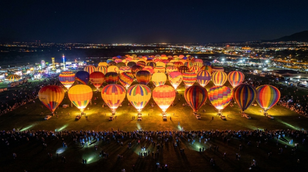 Aerial view of glowing hot air balloons tethered to the ground at night during the Albuquerque Balloon Fiesta Balloon Glow event
